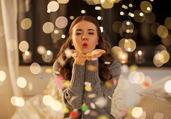 Image showing woman blowing confetti from her hands at night