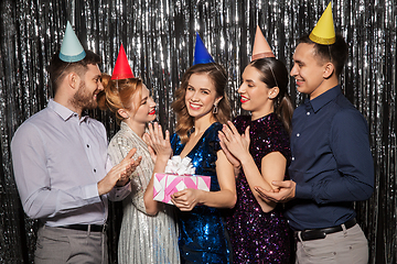 Image showing happy friends in party hats with birthday gift