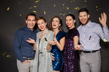 Image showing happy friends at party under confetti over black