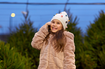 Image showing girl calling on smartphone over christmas trees