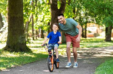 Image showing father teaching little son to ride bicycle at park