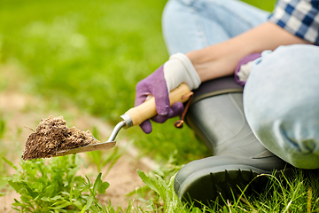 Image showing hand digging flowerbed ground with garden trowel