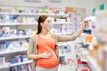 Image showing pregnant woman in mask buys medicine at pharmacy