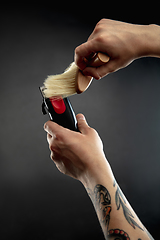 Image showing Hand of male barber with equipment set isolated on black table background.