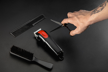 Image showing Hand of male barber with equipment set isolated on black table background.