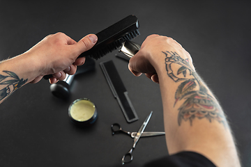 Image showing Hand of male barber with equipment set isolated on black table background.