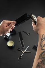 Image showing Hand of male barber with equipment set isolated on black table background.
