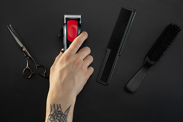 Image showing Hand of male barber with equipment set isolated on black table background.