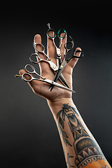 Image showing Hand of male barber with equipment set isolated on black table background.