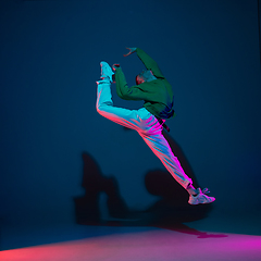 Image showing Stylish sportive boy dancing hip-hop in stylish clothes on colorful background at dance hall in neon light. Youth culture, movement, style and fashion, action.