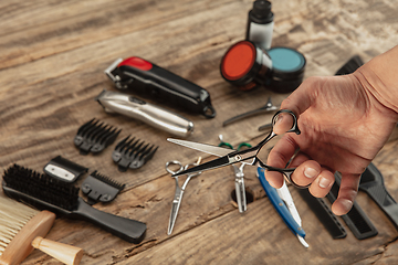 Image showing Hand of male barber with equipment set isolated on wooden table background.