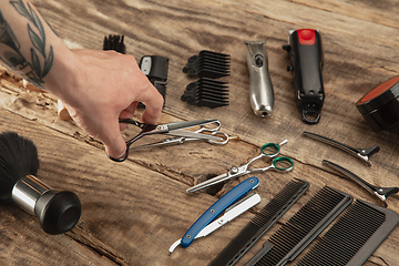 Image showing Hand of male barber with equipment set isolated on wooden table background.