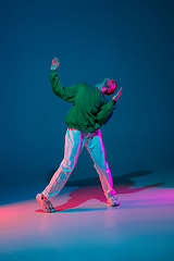 Image showing Stylish sportive boy dancing hip-hop in stylish clothes on colorful background at dance hall in neon light. Youth culture, movement, style and fashion, action.