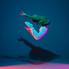 Image showing Stylish sportive boy dancing hip-hop in stylish clothes on colorful background at dance hall in neon light. Youth culture, movement, style and fashion, action.