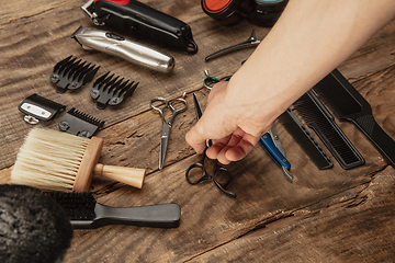 Image showing Hand of male barber with equipment set isolated on wooden table background.