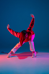 Image showing Stylish sportive girl dancing hip-hop in stylish clothes on colorful background at dance hall in neon light. Youth culture, movement, style and fashion, action.