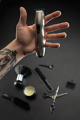 Image showing Hand of male barber with equipment set isolated on black table background.