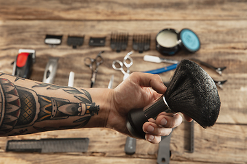 Image showing Hand of male barber with equipment set isolated on wooden table background.