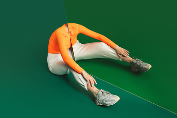 Image showing Female model in sporty outfit on bicolored background with mirror. Style and beauty concept. Close up.