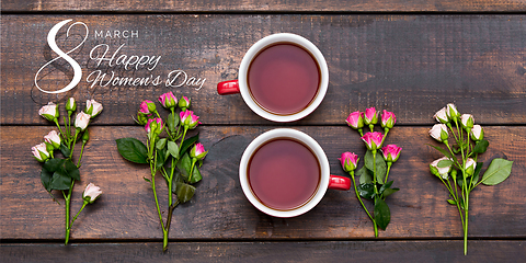 Image showing Two cups of tea in shape of number 8 with flowers over wooden background.