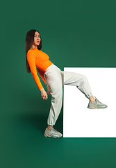 Image showing Female model in sporty outfit on bicolored background with mirror. Style and beauty concept. Close up.