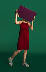 Image showing Female model in red outfit on green background with mirror. Style and beauty concept. Close up.