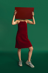 Image showing Female model in red outfit on green background with mirror. Style and beauty concept. Close up.