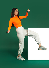 Image showing Female model in sporty outfit on bicolored background with mirror. Style and beauty concept. Close up.