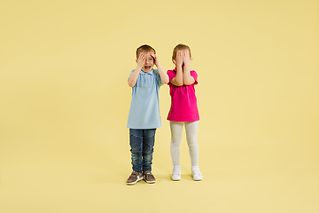 Image showing Childhood and dream about big and famous future. Pretty little kids isolated on yellow studio background