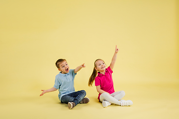 Image showing Childhood and dream about big and famous future. Pretty little kids isolated on yellow studio background