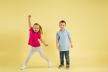 Image showing Childhood and dream about big and famous future. Pretty little kids isolated on yellow studio background