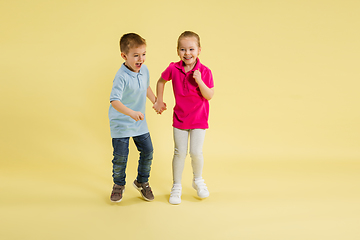 Image showing Childhood and dream about big and famous future. Pretty little kids isolated on yellow studio background