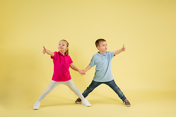 Image showing Childhood and dream about big and famous future. Pretty little kids isolated on yellow studio background