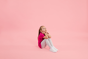 Image showing Childhood and dream about big and famous future. Pretty little girl isolated on coral pink background