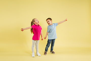 Image showing Childhood and dream about big and famous future. Pretty little kids isolated on yellow studio background