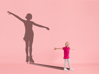 Image showing Childhood and dream about big and famous future. Conceptual image with girl and shadow of fit female figure skater on coral pink background