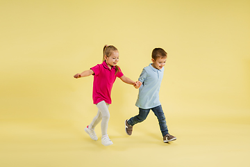 Image showing Childhood and dream about big and famous future. Pretty little kids isolated on yellow studio background