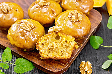 Image showing Cupcake pumpkin with orange glaze and walnuts on brown board