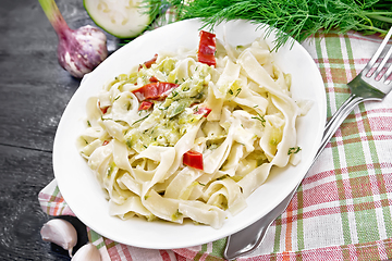 Image showing Fettuccine with zucchini and hot peppers in plate on black woode