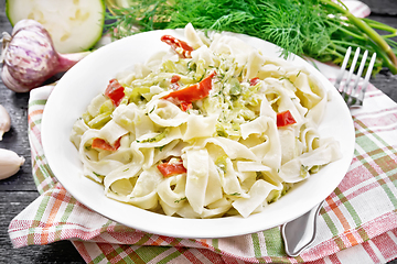 Image showing Fettuccine with zucchini and hot peppers in plate on wooden boar