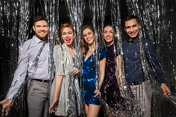 Image showing happy friends in party clothes with tinsel curtain