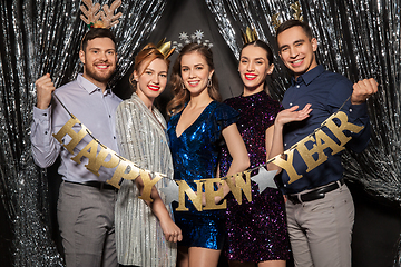 Image showing happy friends posing with new year banner