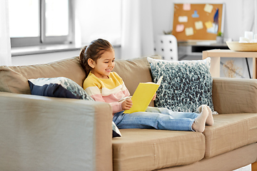 Image showing happy smiling little girl reading book at home