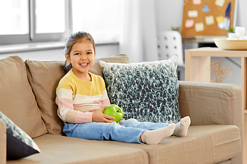 Image showing happy little girl with apple sitting on sofa