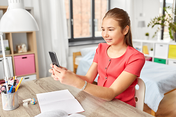 Image showing girl with smartphone distracting from homework