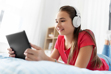 Image showing girl in headphones listening to music on tablet pc