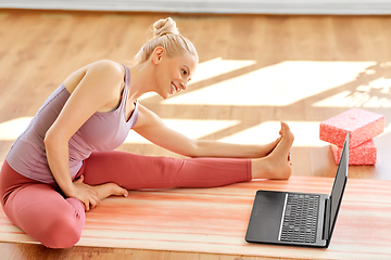 Image showing woman with laptop exercising at yoga studio