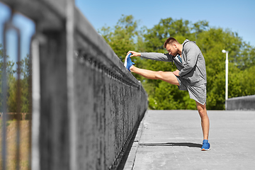 Image showing man stretching leg on bridge