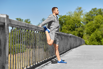 Image showing man stretching leg on bridge