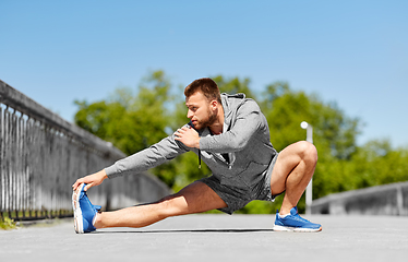 Image showing man stretching leg on bridge